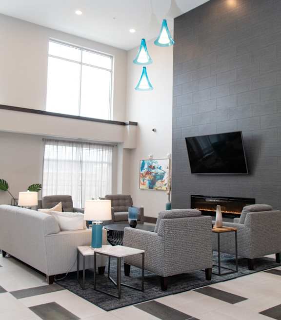 A living room with a grey couch, a fireplace, and a television.at The Edison at Avonlea, Minnesota, 55044