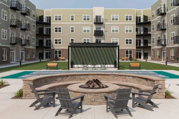 A fire pit surrounded by chairs in a courtyard.