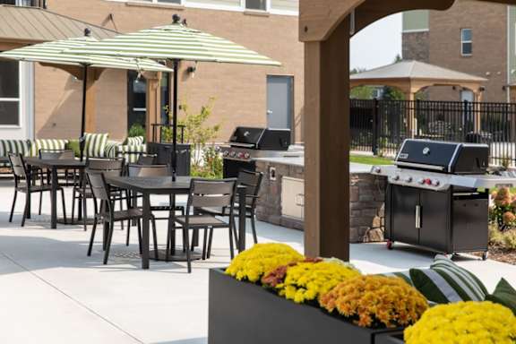 A patio with a table, chairs and a grill.