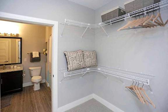 A bathroom with a toilet, sink, and a pillow on a shelf.