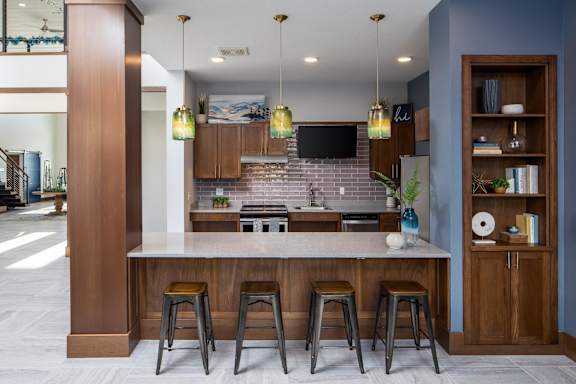 A kitchen with a bar area and a television mounted above the island.
