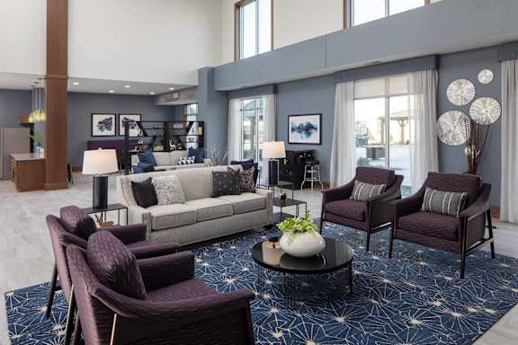 A living room with a grey couch, a white coffee table, and a blue rug.