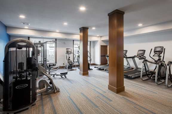 A gym with a variety of equipment including treadmills, weights, and exercise machines.