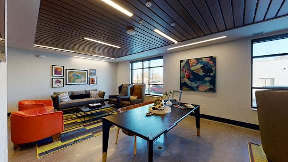 A modern living room with a wooden ceiling and a large painting on the wall at The Bessemer at Seward Commons Apartments, Minnesota