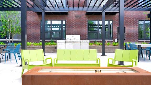 A green bench is in the middle of a courtyard at The Bessemer at Seward Commons Apartments, MN, 55404