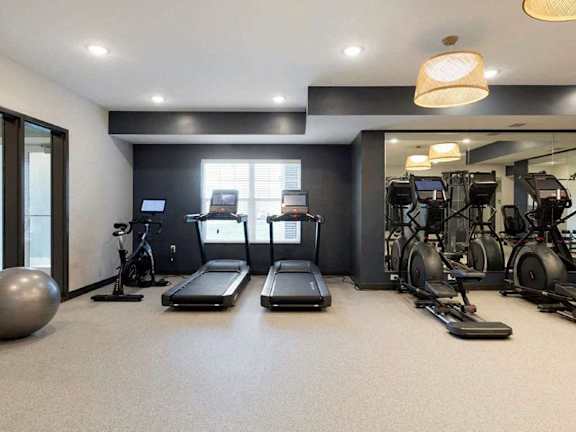 A gym with treadmilers, exercise bikes, and a large ball at The Barnum Apartments, White Bear Lake, 55110