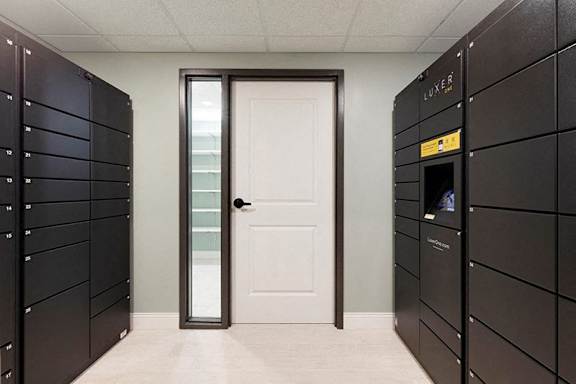 A hallway with a white door and a wall of lockers on the left at The Barnum Apartments, White Bear Lake, Minnesota