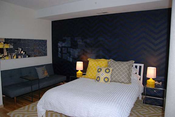 A bedroom with a large bed and a grey couch.