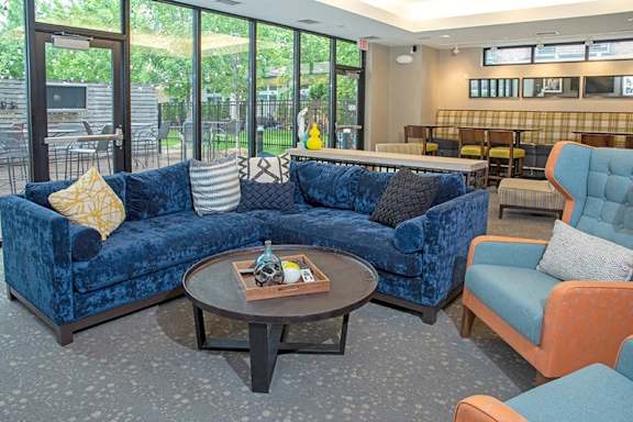 A blue velvet couch with a coffee table in front of it.