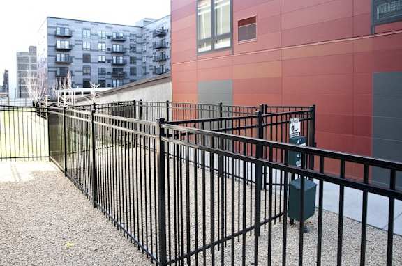 A black metal fence in front of a red building.