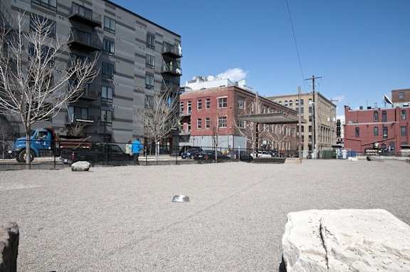 A large open square with a large rock in the foreground and apartment buildings in the background.
