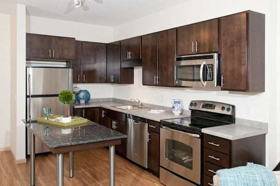 A kitchen with a stainless steel refrigerator, microwave, oven, and dishwasher.