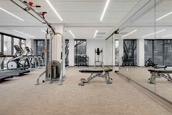 A gym with a variety of equipment including treadmills, weights, and benches.at Viridium Apartments, Minneapolis, MN