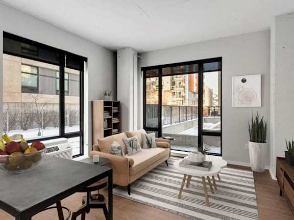 A modern living room with a large window and a view of a snowy landscape outside.at Viridium Apartments, Minneapolis, 55401