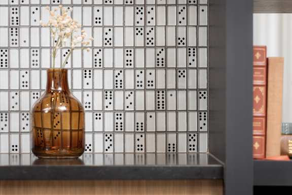 A brown vase with white flowers sits on a shelf.