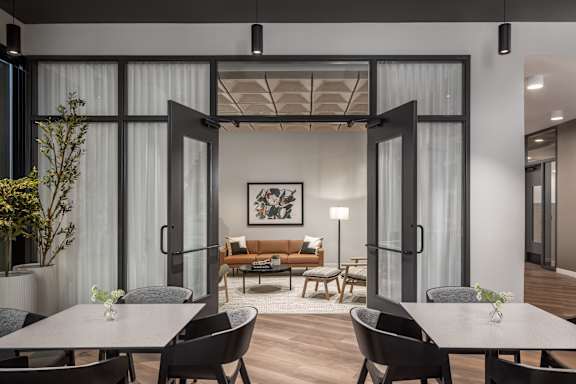 A modern dining room with a glass partition and a wooden floor.