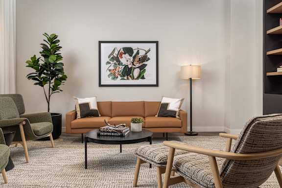 A living room with a brown couch, a coffee table, and a framed picture on the wall.
