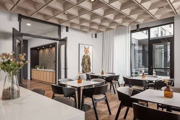 A modern dining room with a white table and black chairs.