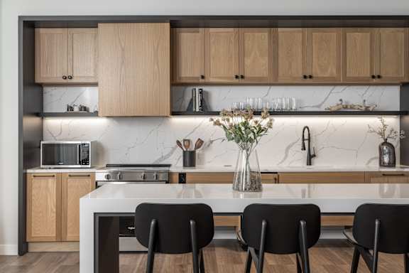 A modern kitchen with wooden cabinets and a marble backsplash.