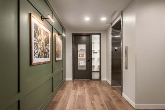 A hallway with a wooden floor and a black door.