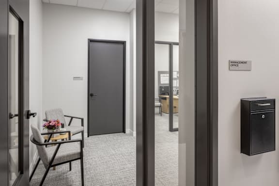 A black door is in a white hallway.