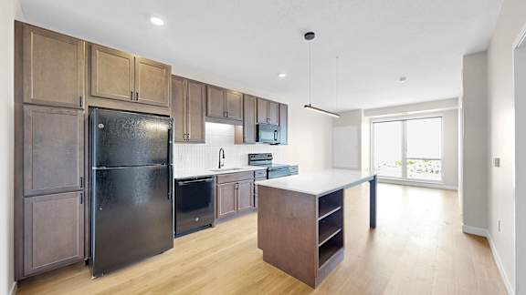 A kitchen with wooden cabinets and a black fridge.