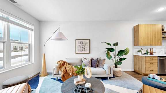 A modern living room with a large window, a white sofa, and a coffee table.