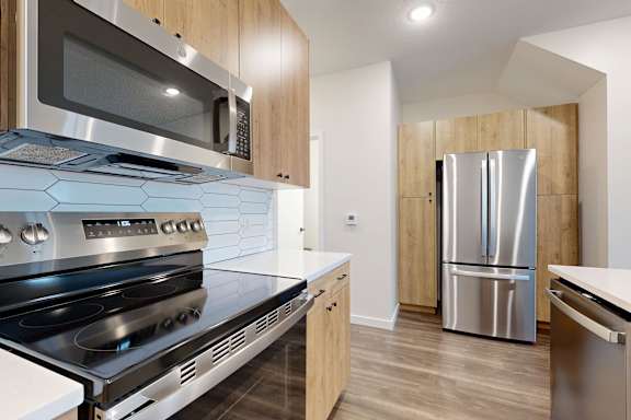 A modern kitchen with stainless steel appliances and wooden cabinets.