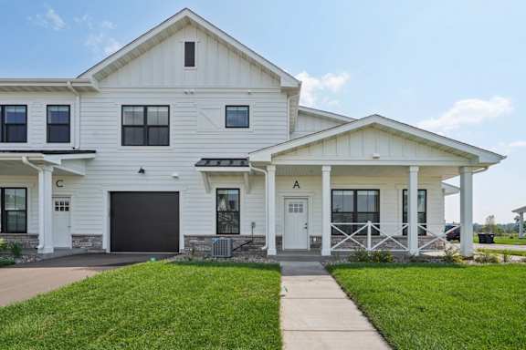 A white house with a black garage door and a white front door.