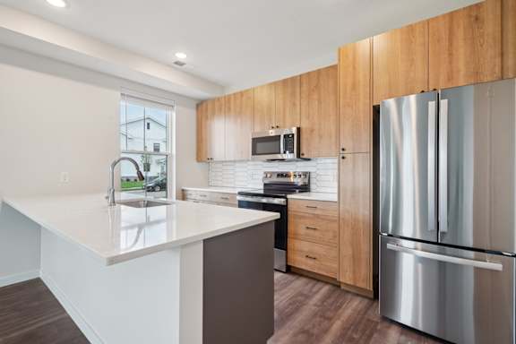 A modern kitchen with a refrigerator, microwave, and oven.
