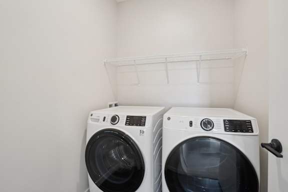 Two white front loading washing machines in a laundry room.