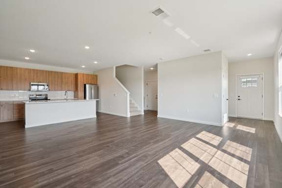 A spacious living room with a kitchen area in the background.