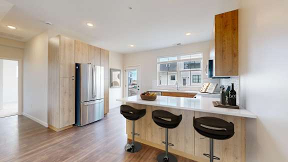 A kitchen with a bar stool and a fridge.