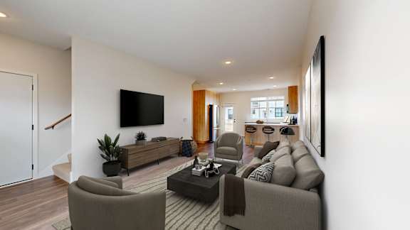 A living room with a grey couch and a television on the wall.