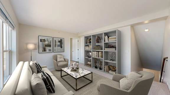 A living room with a grey sofa, a coffee table, and a bookshelf.