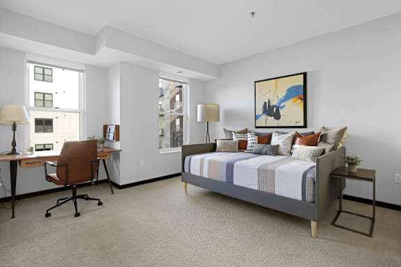 A bedroom with a bed, desk, and chair.
