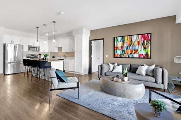 A modern living room with a grey couch and a large abstract painting on the wall.
