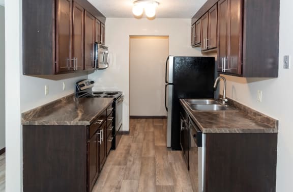 a kitchen with dark wood cabinets and stainless steel appliances