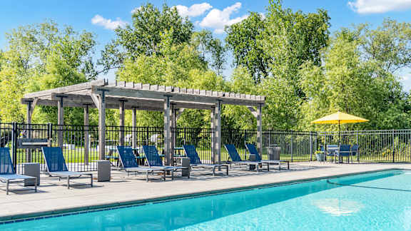 A pool area with a sunshade and chairs.