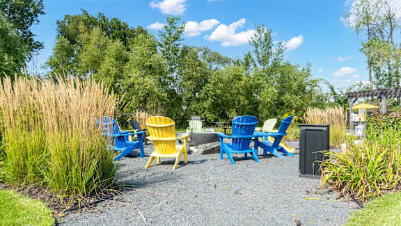 A gravel area with blue and yellow chairs and a trash can.