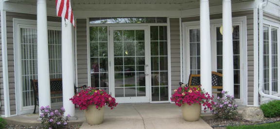 a porch with two pillars and two potted flowers  at Briarcliff Apartments, a 55+ Community, Mahtomedi, 55115