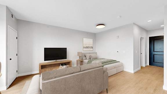 A living room with a grey couch and a television on a wooden stand.