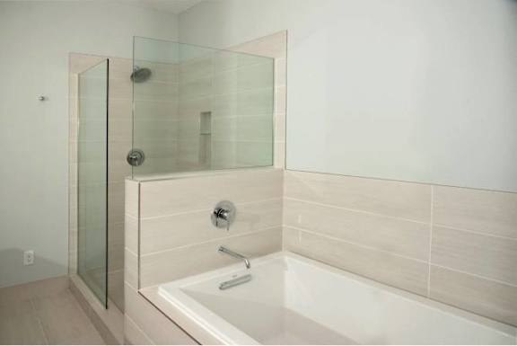 A white bathroom with a glass shower door and a white tub.