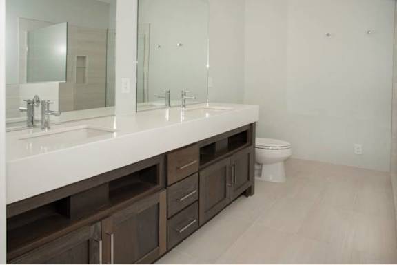 A bathroom with a white counter top and brown drawers.