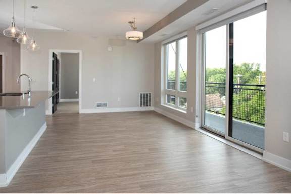 A spacious living room with wooden flooring and large windows.