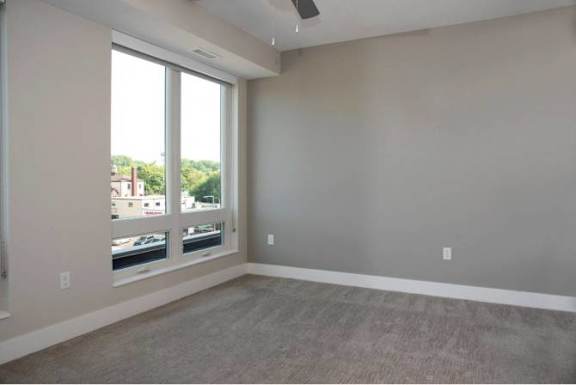 A room with a large window and a ceiling fan.