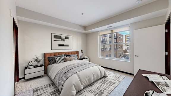 A bedroom with a large bed and a window overlooking a cityscape.