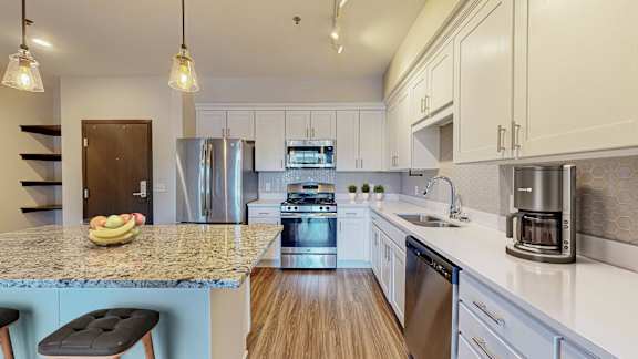 A kitchen with a granite countertop and stainless steel appliances.