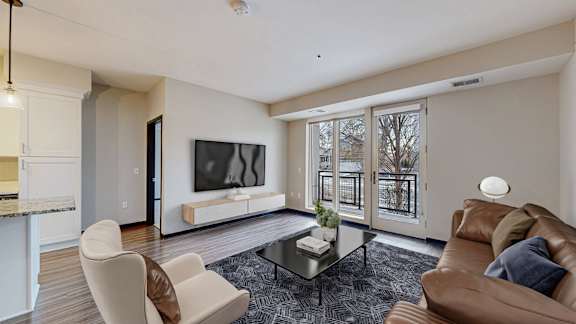 A living room with a brown couch, a white chair, and a glass coffee table.