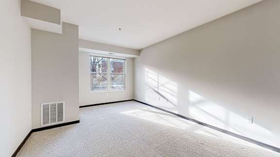 A large empty room with a window and a door.